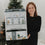 Frau mit Eulenschnitt Adventskalender vor festlich geschmücktem Weihnachtsbaum in gemütlicher Atmosphäre.