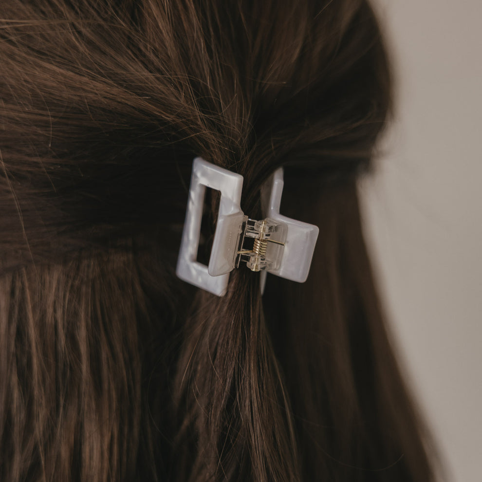 Kleine eckige Haarspange in Perlmutt-Optik im braunen Haar von hinten getragen