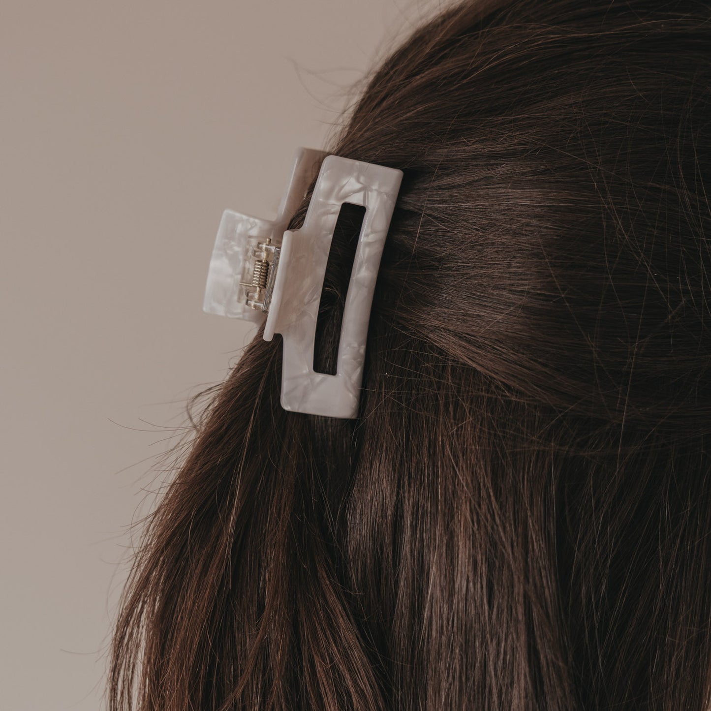 Detail der großen Haarspange eckig in Perlmutt-Optik im braunen Haar