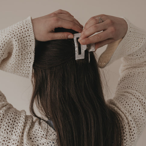 Hände befestigen große eckige Haarspange in Perlmutt-Optik im Haar