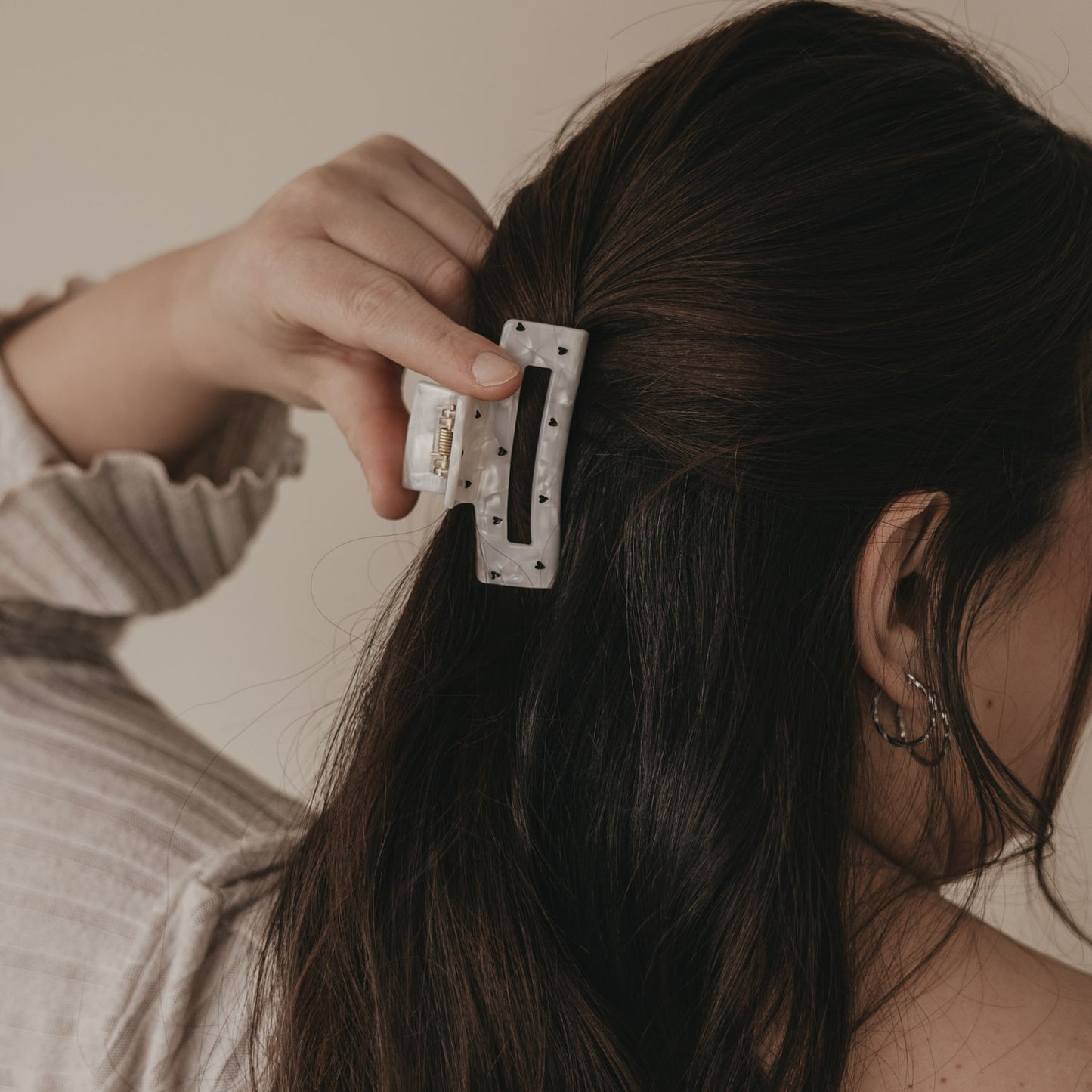 Große eckige Haarspange in Perlmutt-Optik mit schwarzen Herzen im halboffenen Haar