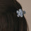 Detail Haarspange Blume hellblau im braunen Haar mit glänzender Oberfläche