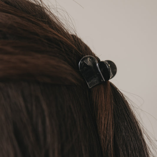 Detail kleine Haarspange Herzform schwarz im braunen Haar