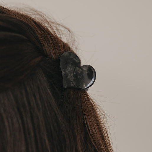 Große Haarspange in Herzform schwarz im braunen Haar getragen, seitliche Detailansicht