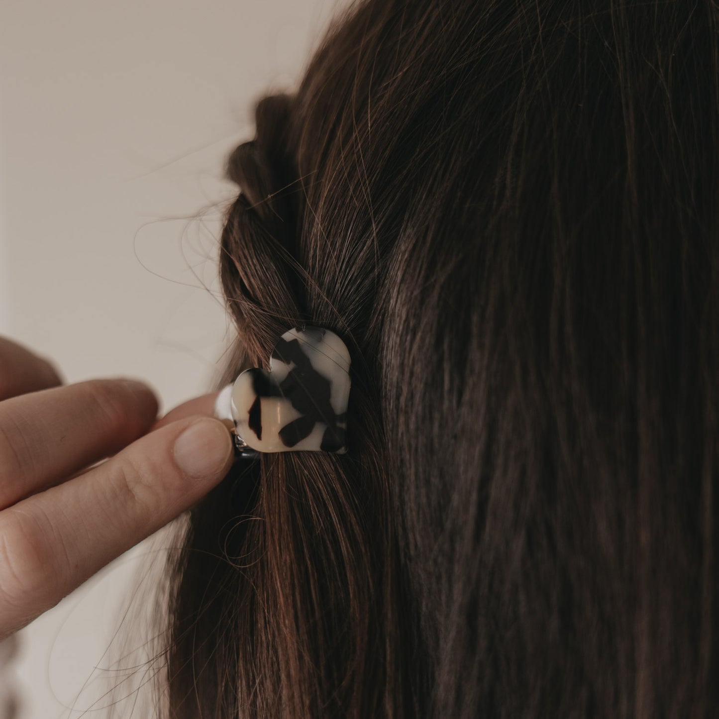 Kleine Haarspange in Herzform mit Leo-Muster wird ins braune Haar eingesetzt