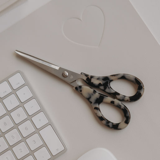 Silberne Schere mit Leo-Griff auf Schreibtisch neben Tastatur und Maus