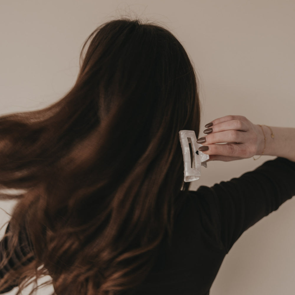 Große eckige Haarspange mit schwarzem Herz hält braunes Haar zusammen