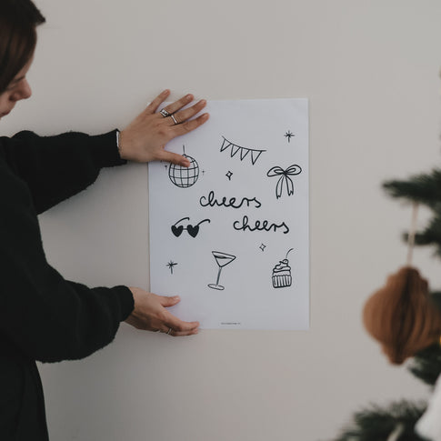 Frau hält Winter cheers Poster an die Wand. Modernes Poster für Küche, Esszimmer, Barbereich oder Homeoffice oder als geschmackvolles Geschenk zu Geburtstagen, Dinnerpartys oder Feiern aller Art.