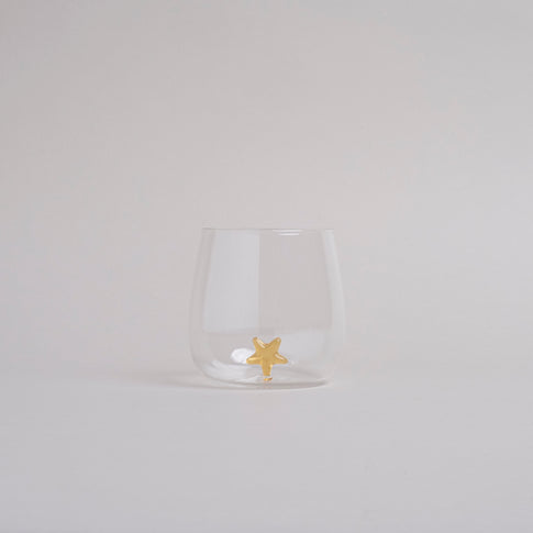 Klares Trinkglas mit goldfarbener Sternfigur am Boden, modernes Design