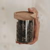 Mini Vorratsglas mit Punkten und Holzdeckel, gefüllt mit Schokoraspeln und in der Hand gehalten