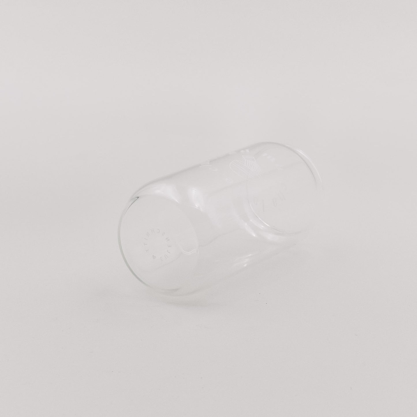 Transparentes Glas mit minimalistischem Matcha-Print liegt seitlich auf hellem Untergrund. Das schlichte Design wirkt modern und dezent.