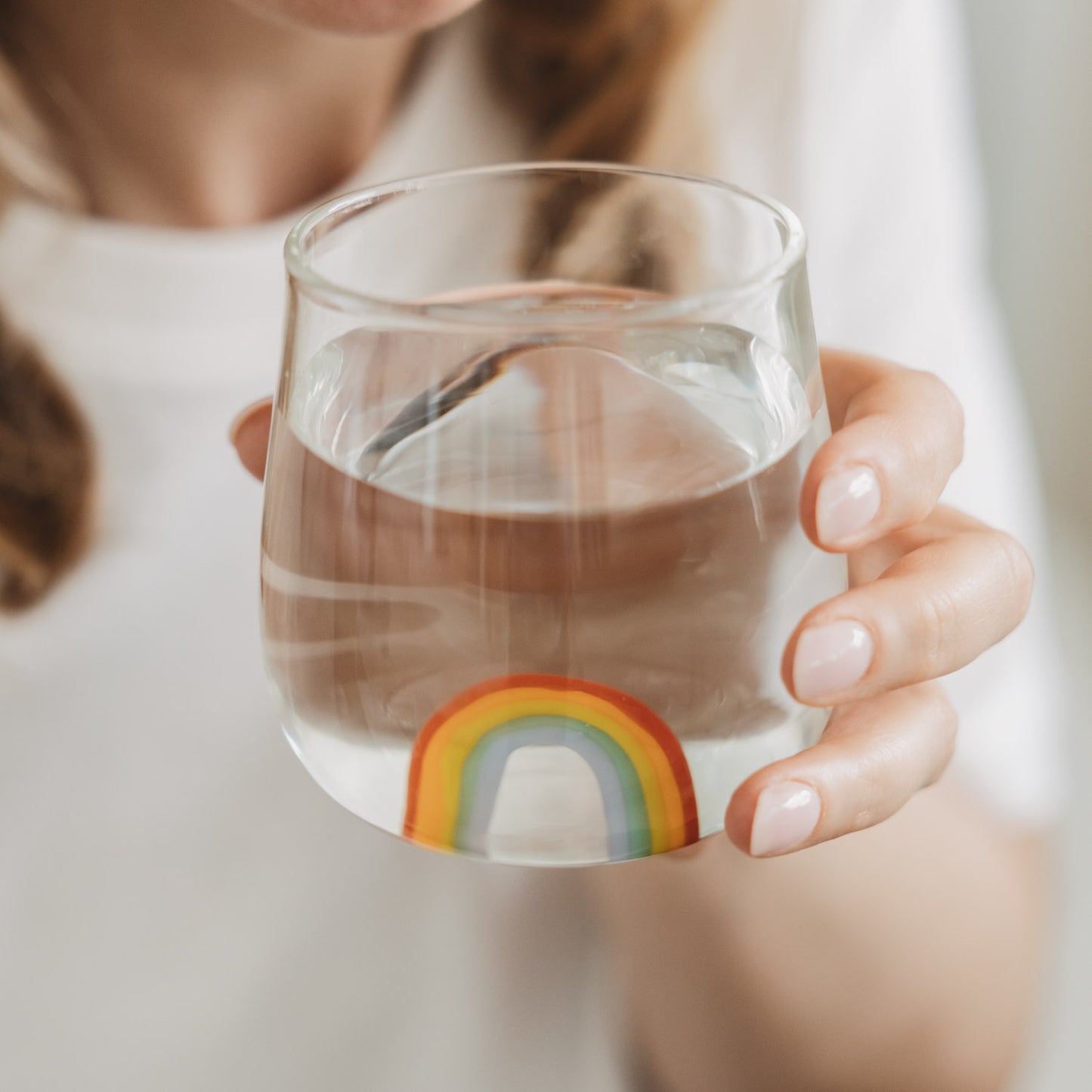 Hand hält Glas mit Regenbogen Motiv, stilvolles Trinkglas für Wasser im Alltag
