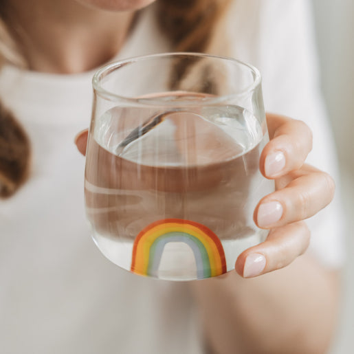 Hand hält Glas mit Regenbogen Motiv, stilvolles Trinkglas für Wasser im Alltag