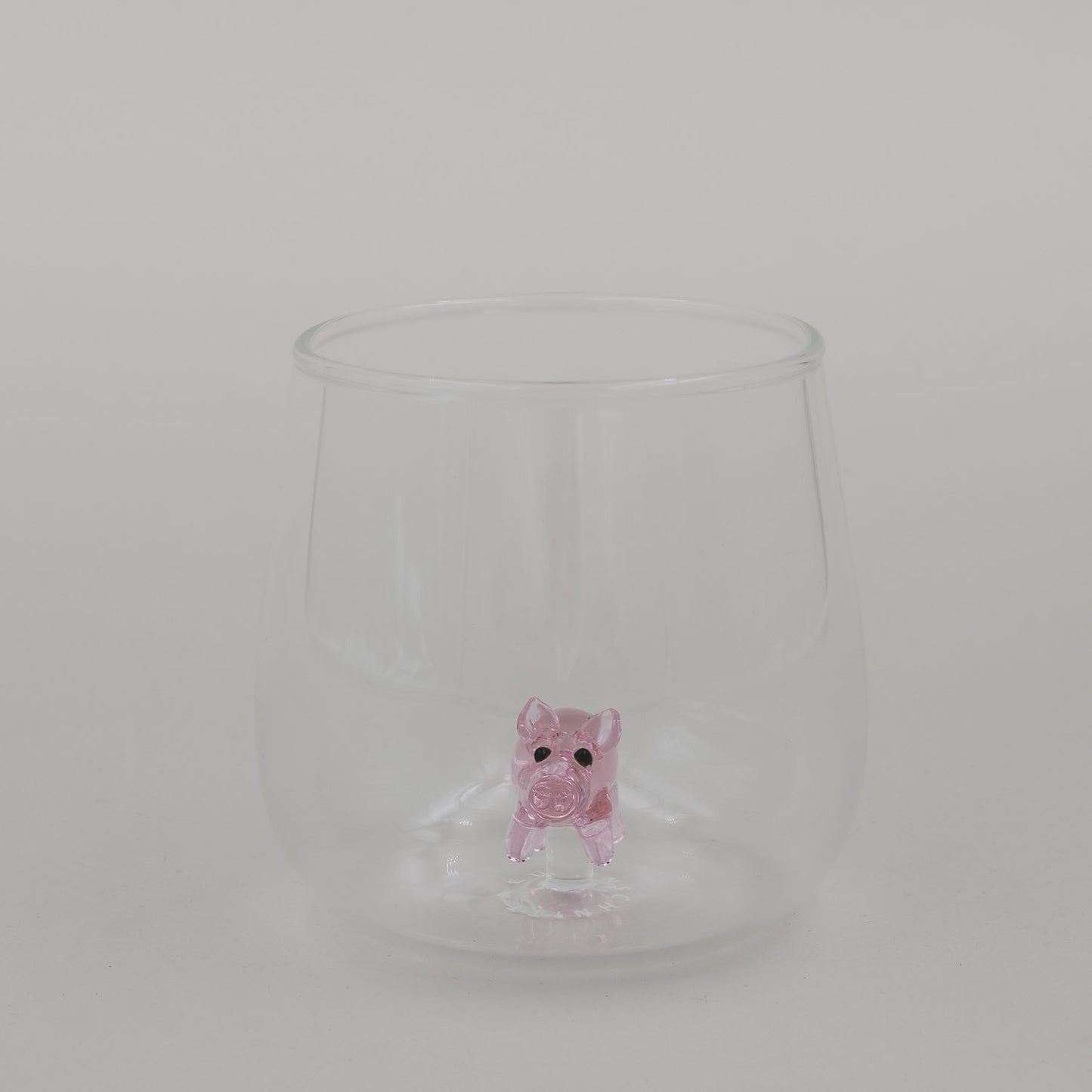 Freigestelltes Trinkglas mit Schwein Figur im Boden, minimalistisches Glasdesign