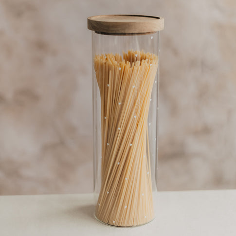Hohes Vorratsglas mit kleinen weißen Herzen und Holzdeckel, gefüllt mit Spaghetti.