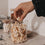 Hand greift nach Popcorn aus einem Glasbehälter mit kleinen schwarzen Herzen.
