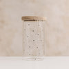 Leeres hohes Vorratsglas mit kleinen schwarzen Herzchen und geschlossenem Holzdeckel.