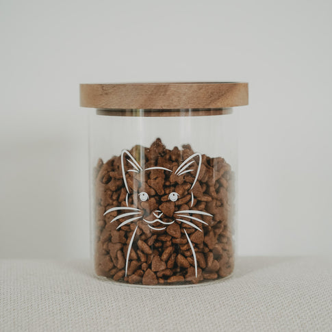 Vorratsglas mit weißem Katzenmotiv, Holzdeckel und Trockenfutter als freigestellte Produktaufnahme.