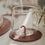 Transparentes Figurenglas mit rot-weißer Zuckerstange im Glasboden auf einem braunen Untersetzer.