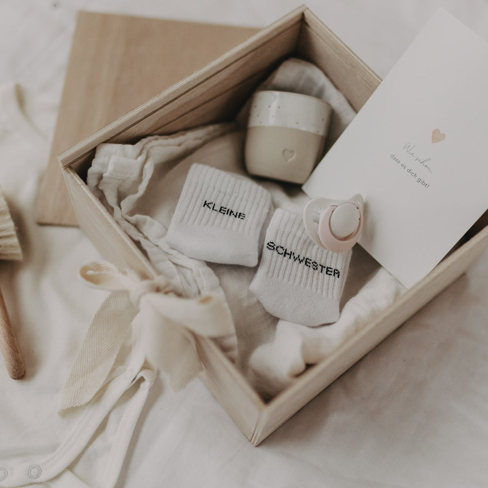 Detailaufnahme der geöffneten Erinnerungsbox Herz mit Babysöckchen, Schnuller und Karte.