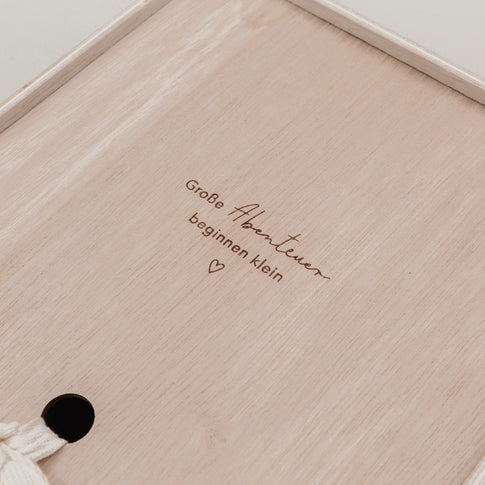 Detailaufnahme der Holzgravur „Große Abenteuer beginnen klein“ auf der Erinnerungsbox.