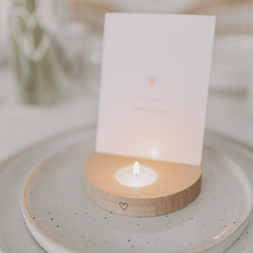 Teelicht-Kartenhalter aus Holz mit brennendem Teelicht und eingesetzter Karte auf gedecktem Tisch.
