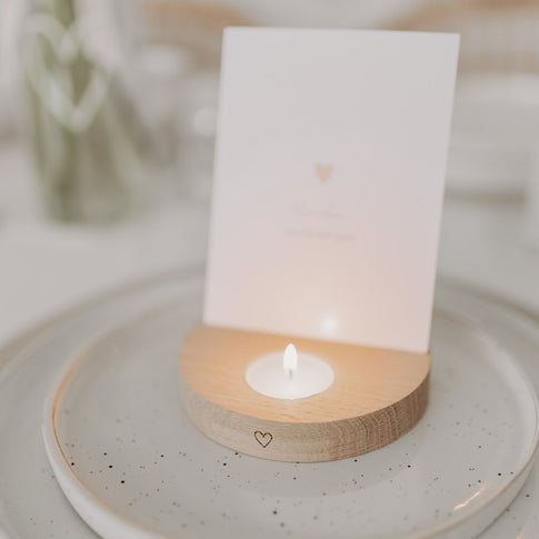 Teelicht-Kartenhalter aus Holz mit brennendem Teelicht und eingesetzter Karte auf gedecktem Tisch.
