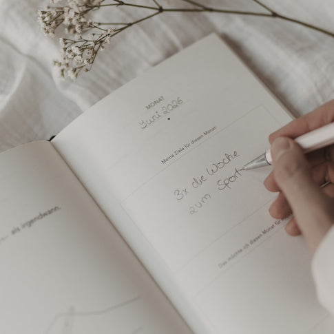 Monatsziel-Seite im Kalender „Neues Glück“ mit handschriftlichem Eintrag und Fokus auf persönliche Ziele