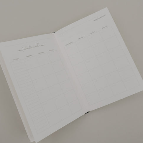 Geöffneter Kalender „Neues Glück“ mit Monatsübersicht und Wochenfeldern im schlichten, minimalistischen Design