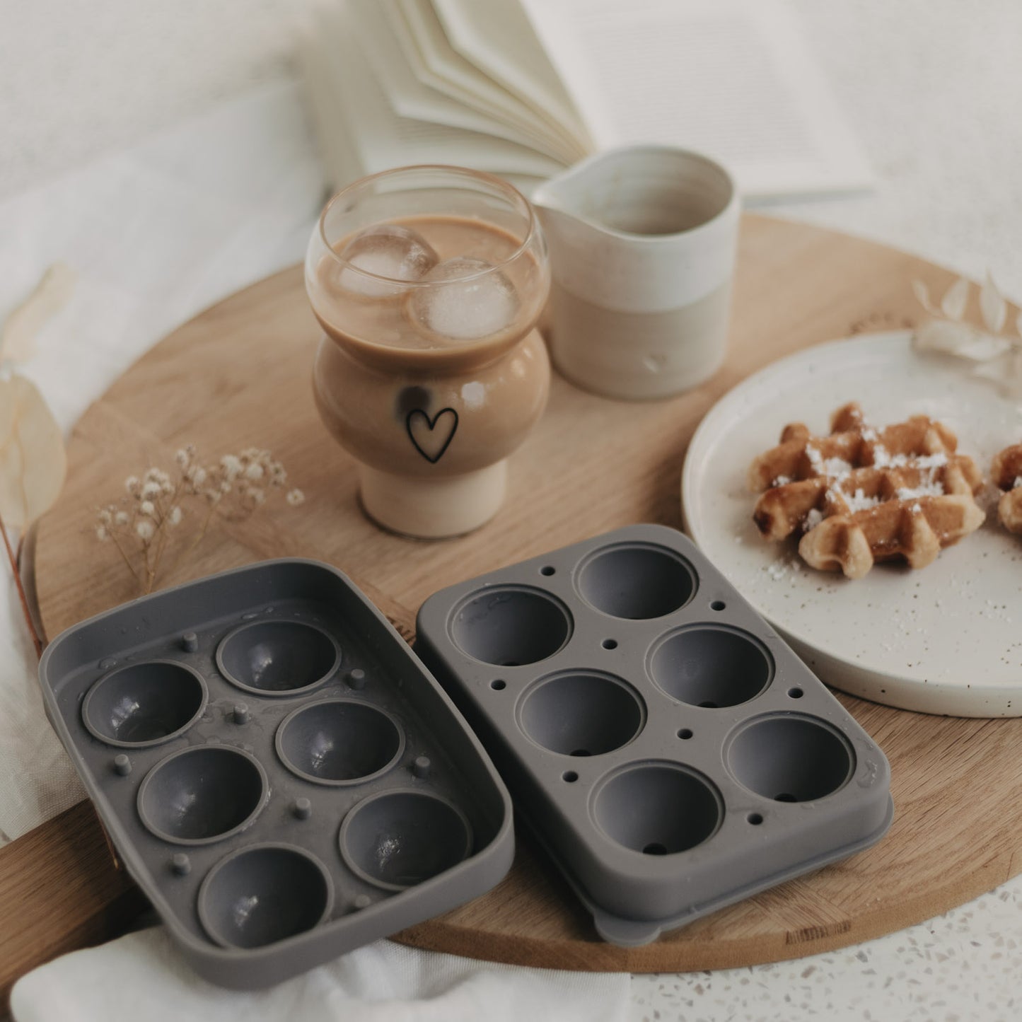 Szenenbild mit geöffneter Form, Glas mit Eis-Kugeln und Waffeln auf Holzbrett.