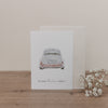 Klappkarte mit Illustration eines weißen Hochzeitsautos von hinten, Nummernschild 'Just Married', Text 'Ein neues Abenteuer beginnt' auf Holzuntergrund mit Schleierkraut