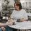 Frau im weißen T-Shirt mit Herz sitzt im Café mit Kaffee und Croissant