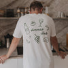 Rückseite des Dinner Club T-Shirts mit grünem Food-Illustrationsdruck in der Küche.