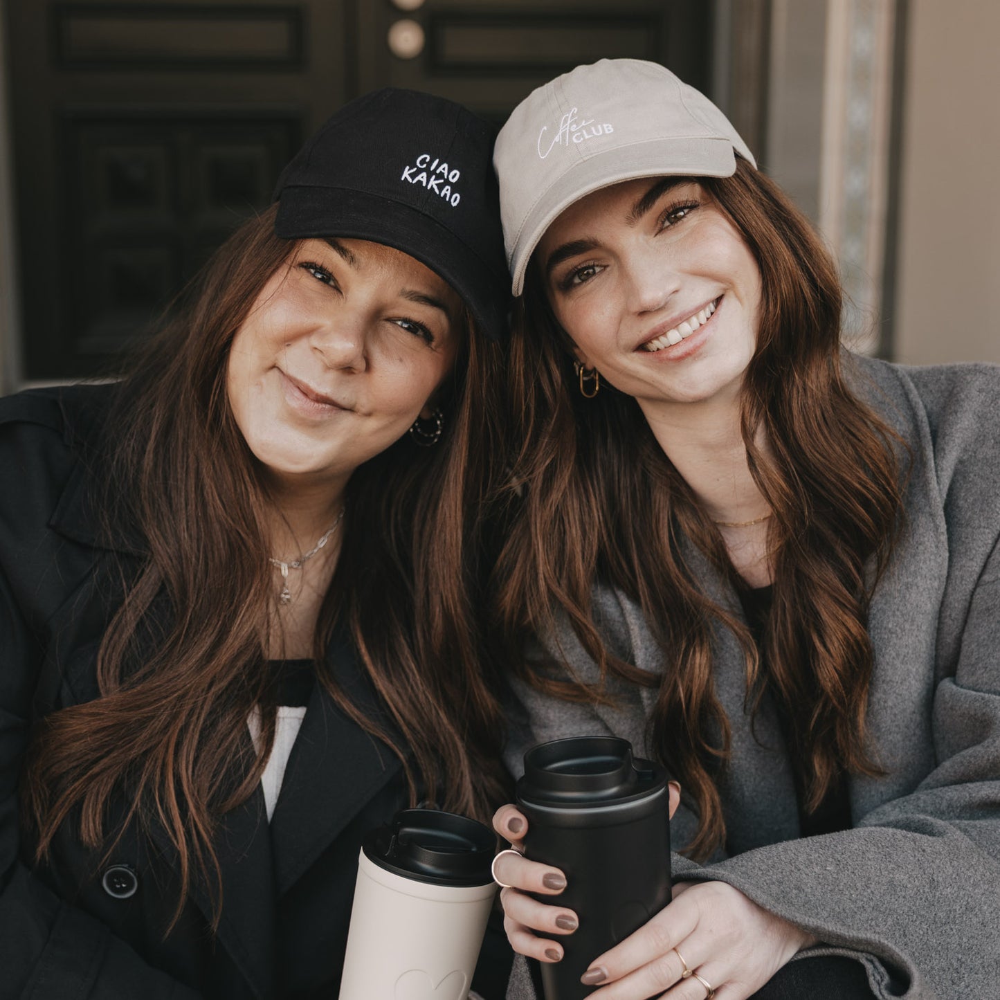 Zwei Frauen mit Caps und Coffee-to-go, eine trägt taupefarbene „Coffee Club“ Cap