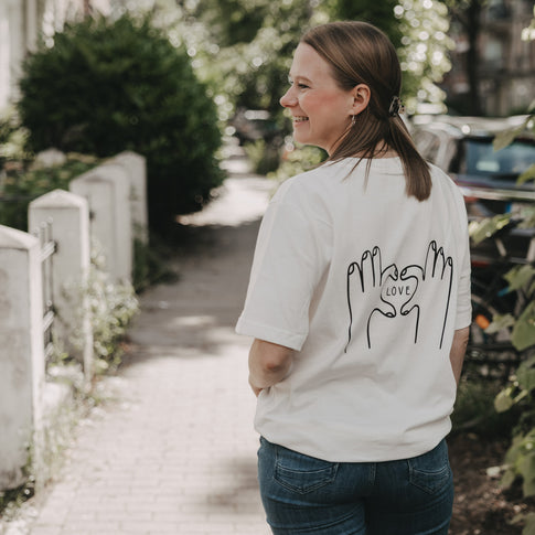 Frau trägt weißes T-Shirt mit LOVE-Print auf dem Rücken, draußen fotografiert
