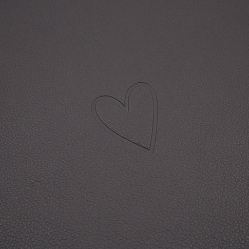 Dunkelgraue Platzset-Oberfläche mit eingeprägtem Herzmotiv in Nahaufnahme.