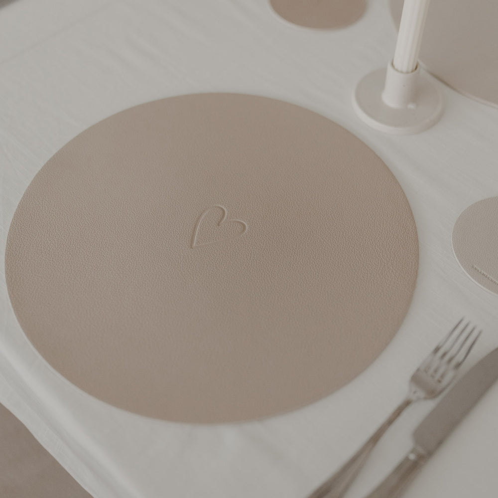 Rundes Platzset in warmem Beige mit geprägtem Herzmotiv als stilvolle Tischdekoration.“