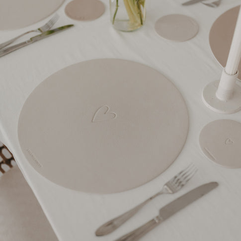 Cremefarbenes Platzset mit Herzprägung und passendem Untersetzer auf hell gedecktem Tisch