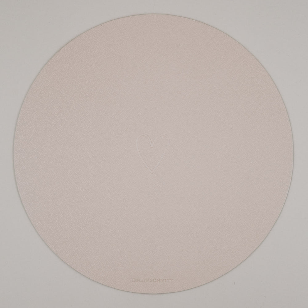 Rundes cremefarbenes Platzset mit geprägtem Herzmotiv auf weißem Hintergrund & Eulenschnitt Logo.