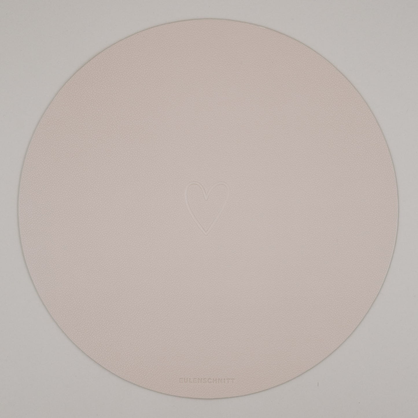 Rundes cremefarbenes Platzset mit geprägtem Herzmotiv auf weißem Hintergrund & Eulenschnitt Logo.