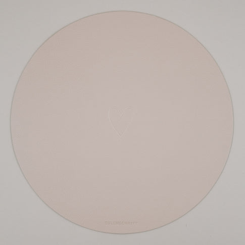 Rundes cremefarbenes Platzset mit geprägtem Herzmotiv auf weißem Hintergrund & Eulenschnitt Logo.