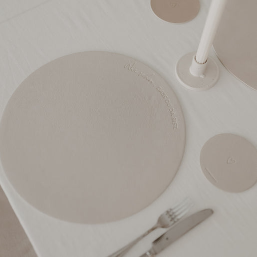 Cremefarbenes Platzset mit Prägung „Wie schön, dass du da bist“ auf gedecktem Tisch.