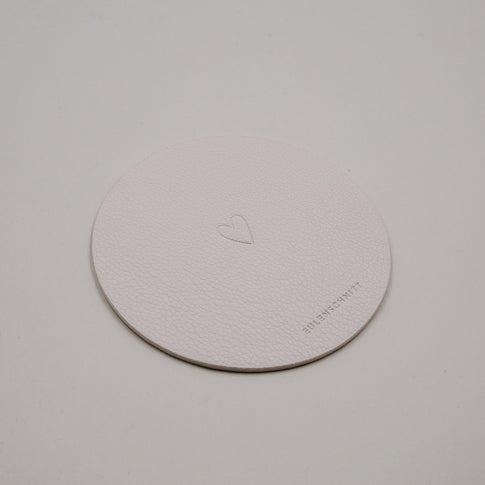 Heller runder Untersetzer aus Kunstleder in Creme mit eingeprägtem Herzmotiv von Eulenschnitt.