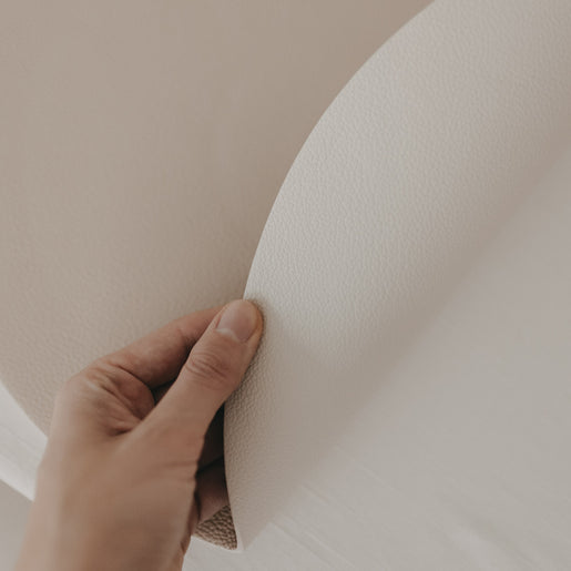 Wendbares cremefarbenes Platzset wird in der Hand gebogen und zeigt die strukturierte Oberfläche.