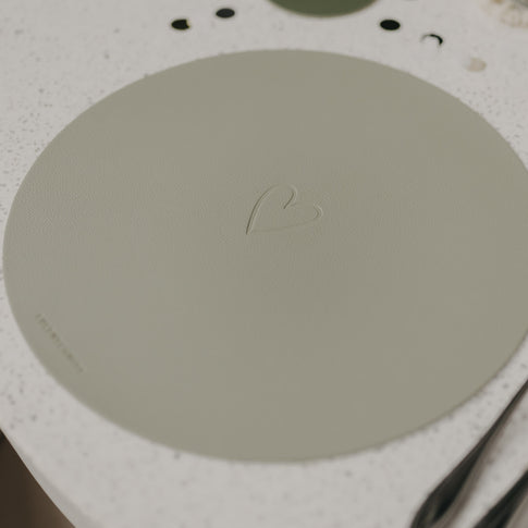 Hellgrünes Platzset Herz Grün auf Tisch, mit eingeprägtem Herzmotiv und Eulenschnitt-Logo.