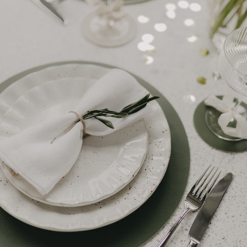 Teller-Set auf dunkelgrünem Platzset mit feiner Herzprägung.