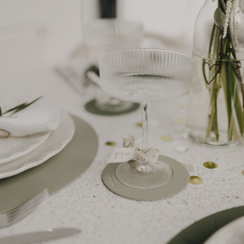 Hellgrüner Untersetzer mit Sektglas und Schleife, stilvoll aufgedeckt.