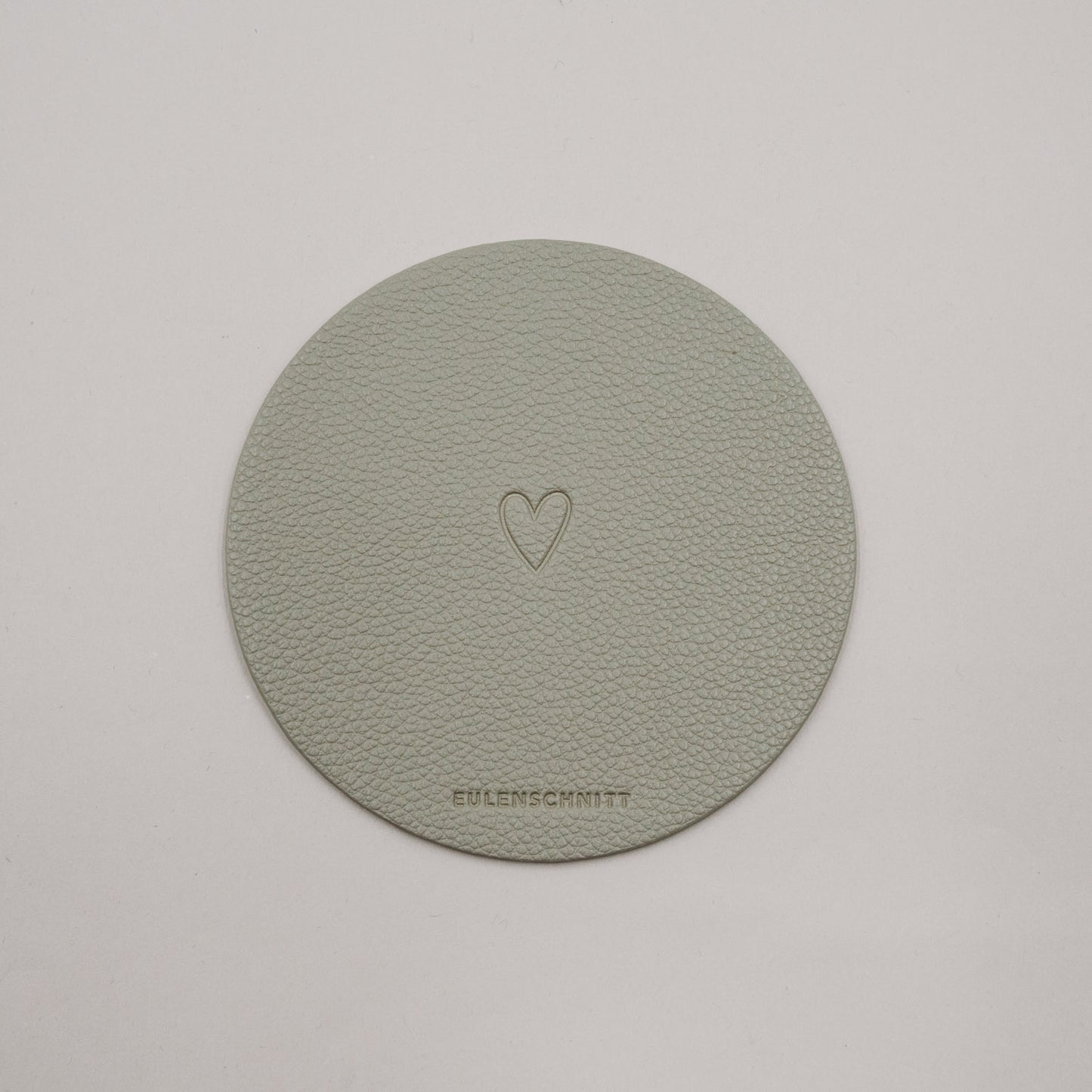 Wendbarer Untersetzer in Hellgrün mit Herzprägung und Eulenschnitt-Logo.