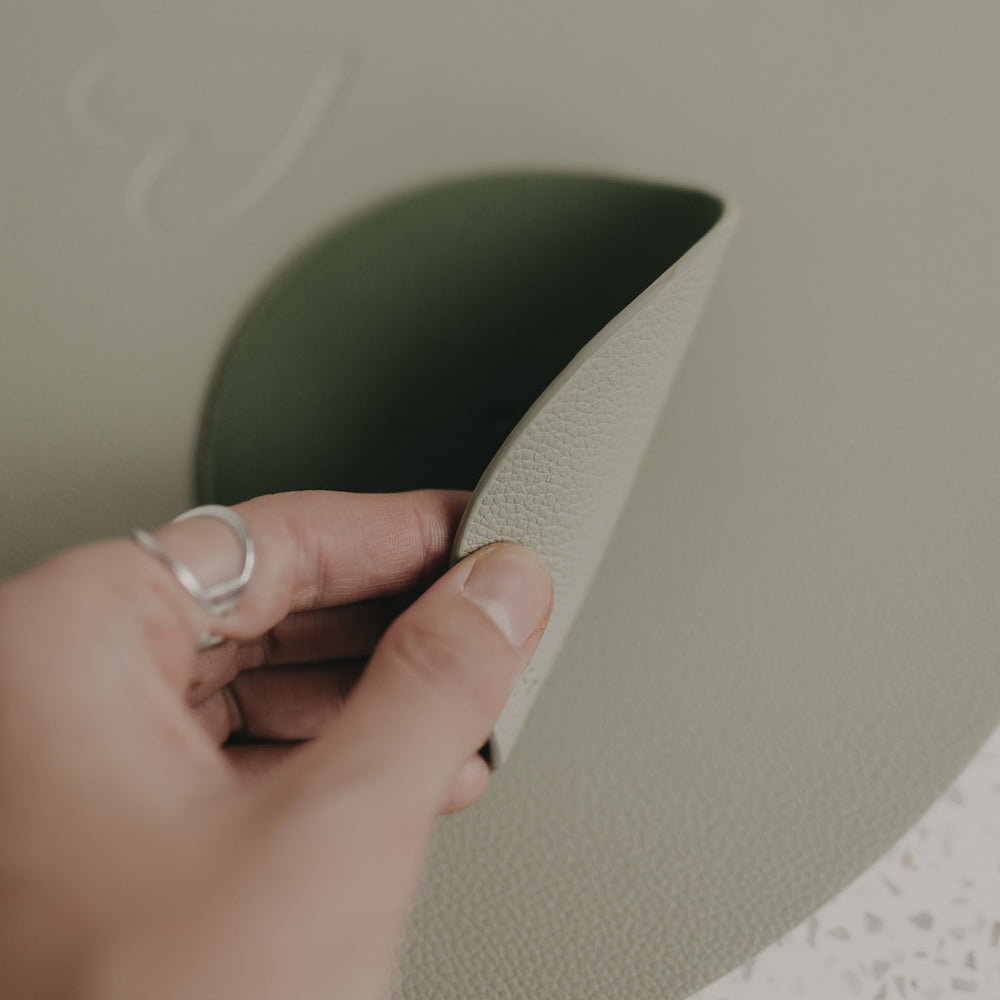 Nahaufnahme: Hand hebt wendbaren Untersetzer in Hell- und Dunkelgrün an.