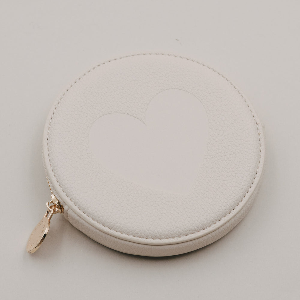 Rundes cremefarbenes Portemonnaie mit großem Herz auf der Vorderseite und goldenem Reißverschluss.